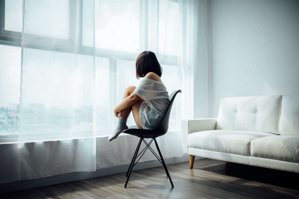 A woman sitting on a chair staring out of the window