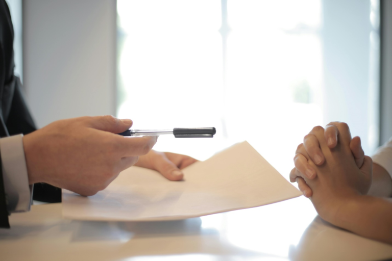 Businessman giving documentation to a woman to sign, illustrating a professional agreement in a corporate environment.