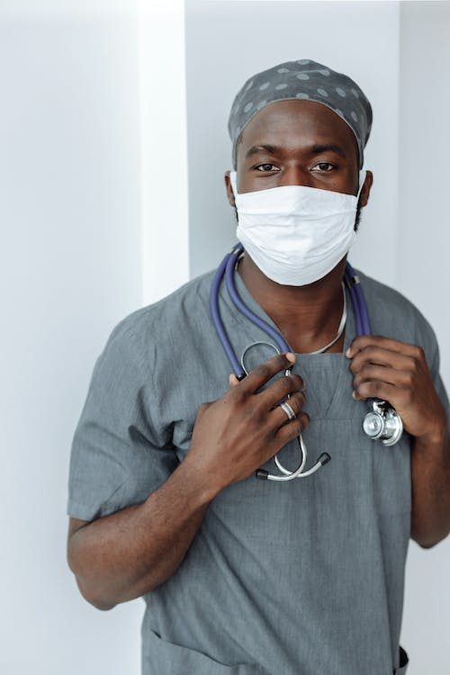 Healthcare worker in gray scrubs with a stethoscope and face mask.