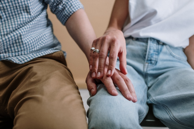 A hand reaches out to touch another, showing the emotional impact of addiction therapy and relational support on those struggling with substance abuse.