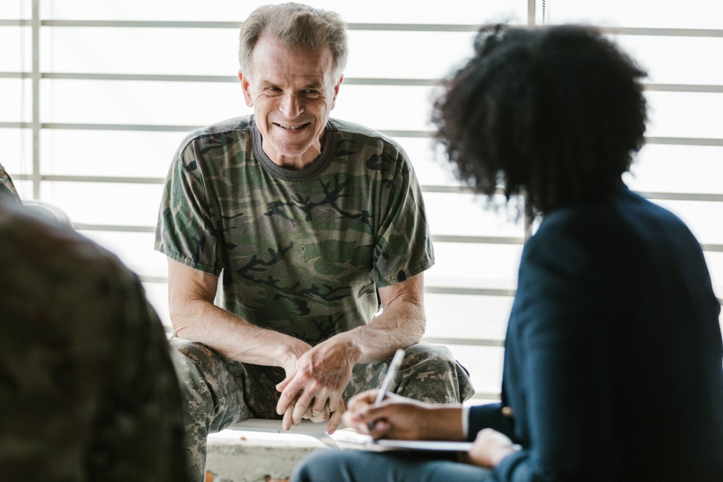 A man in Cammo print smiles at his therapist, showcasing the emotional impact of addiction therapy.