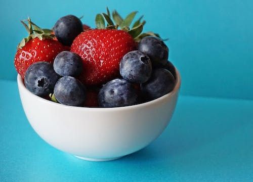 Blueberries and strawberries in a white ceramic bowl