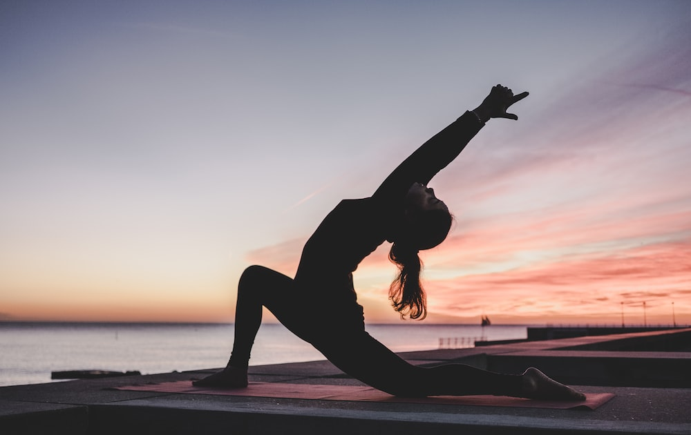 A woman doing yoga at sunrise