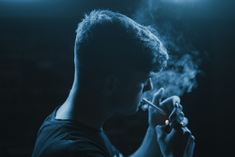 A young man standing and smoking