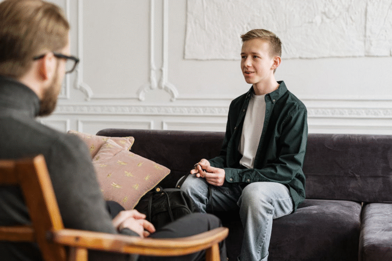 An image of two people sitting on a couch and a chair