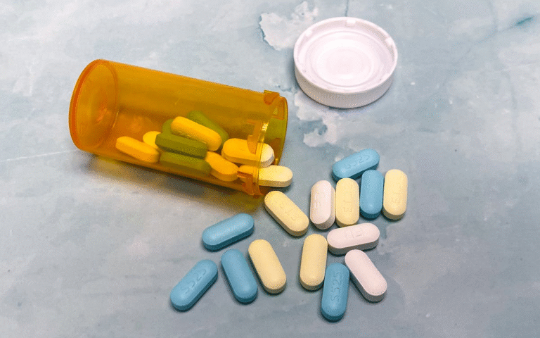 An image of pills coming out of an orange bottle