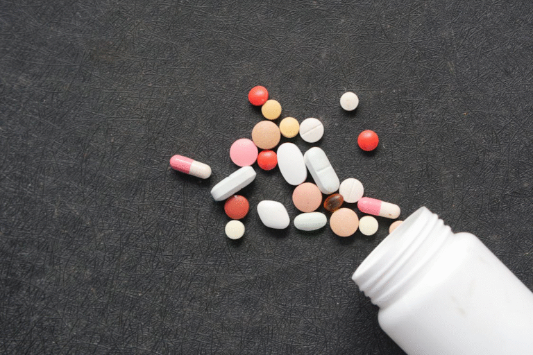 An image of pills coming out of a bottle on a black background