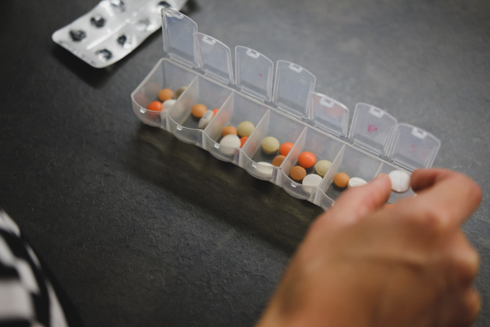 An image of a person taking out pills from a pill box   