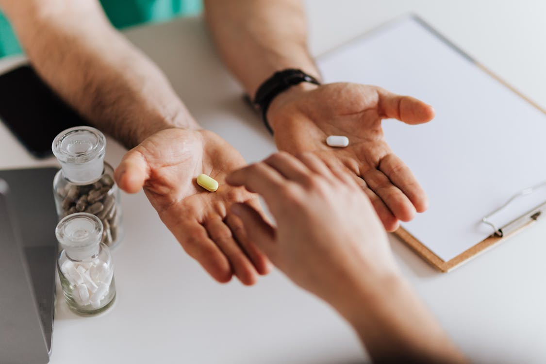 An image of a person offering a choice of pills to another person