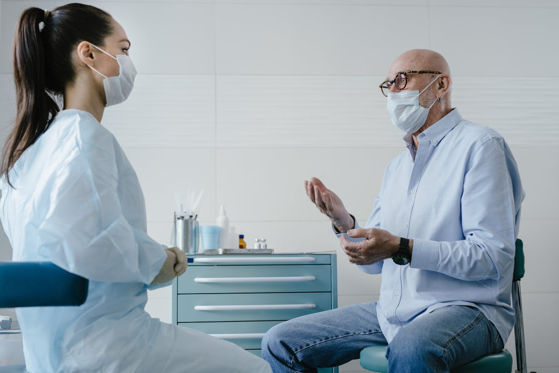 An image of a man talking to a female in a mask and a gown