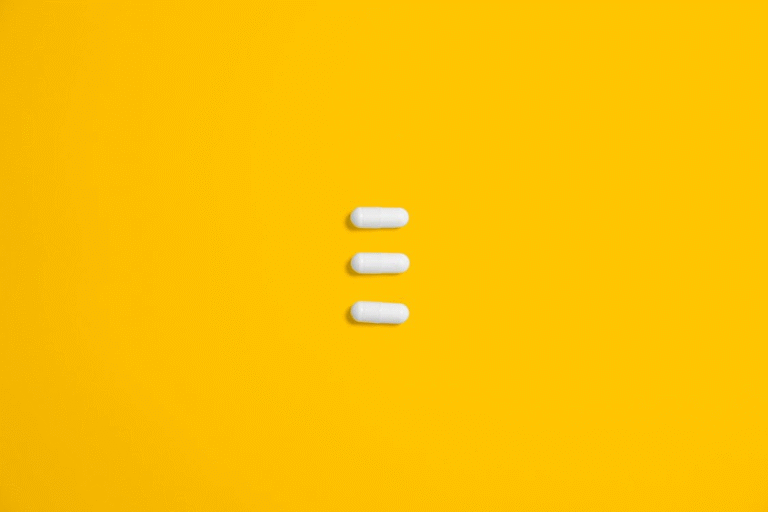 An image of three white pills on an orange background