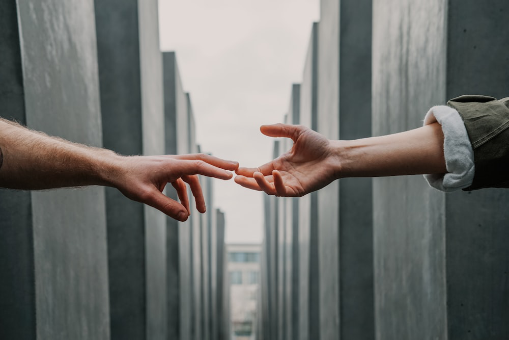 Two individuals reaching out to each other with their hands almost touching.