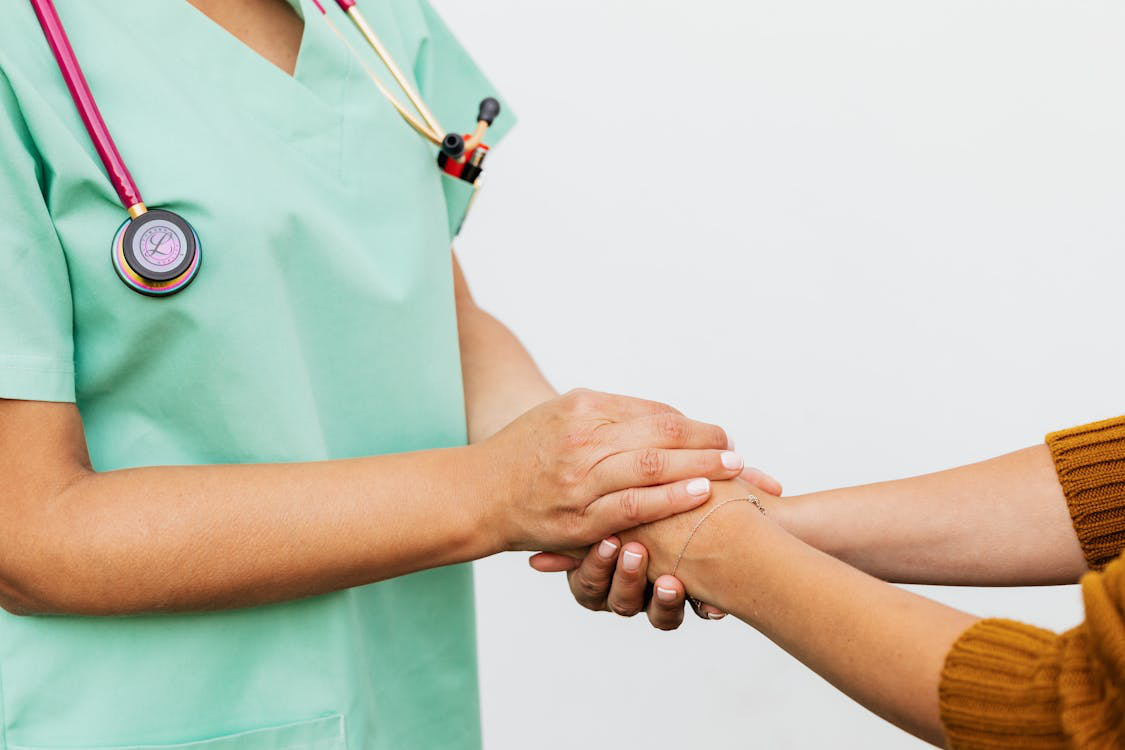 An image of a medical professional and a person holding hands      