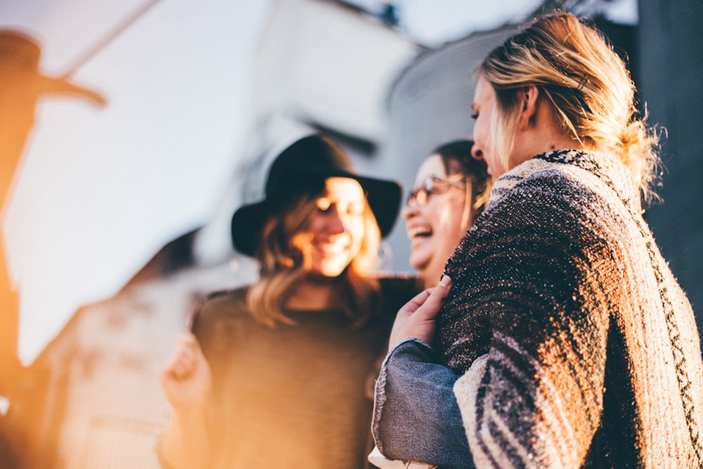  A group of women laughing together in a warm, backlit setting.
