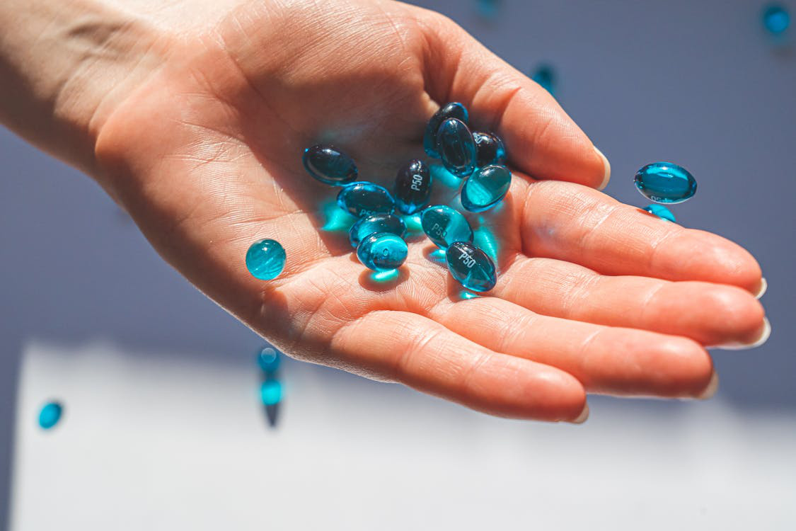 An image of blue pills in a person’s hand