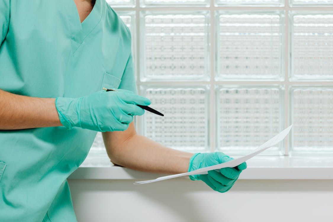 An image of a person holding a pen and a paper in each hand