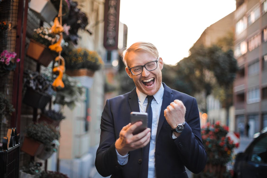 An image of a man in a suit receiving good news