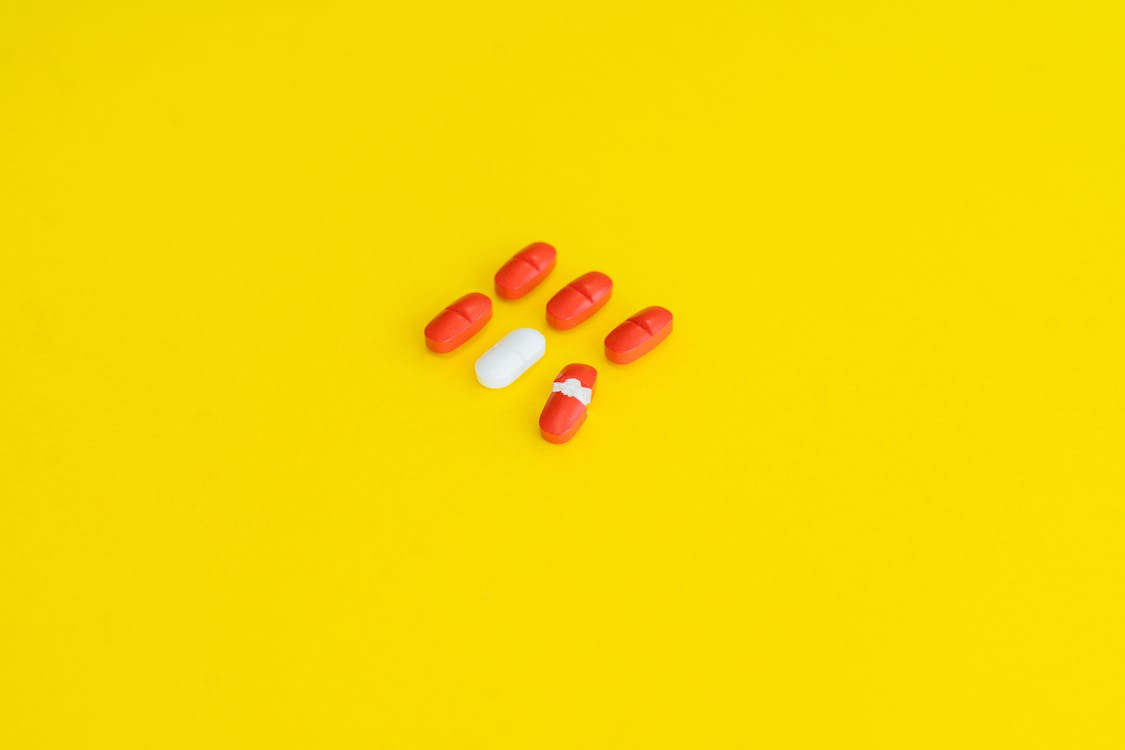 An image of red and white medicine on a yellow surface