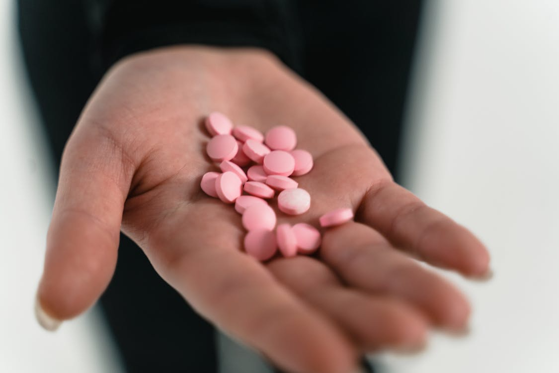 An image of pink pills in a person’s hand