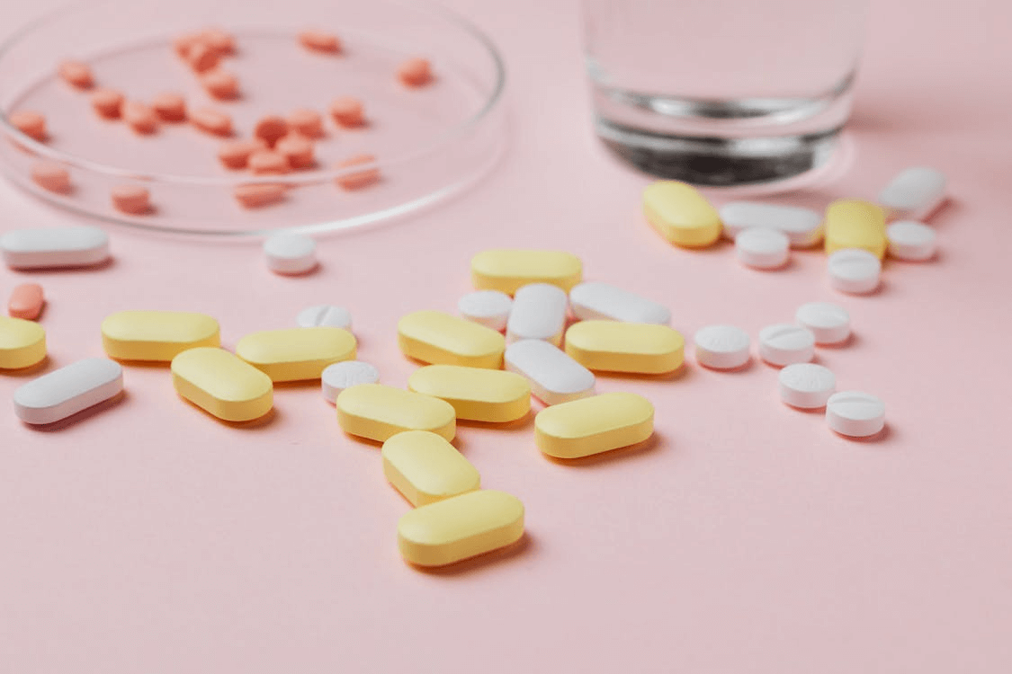 An image of an assortment of pills on a pink surface