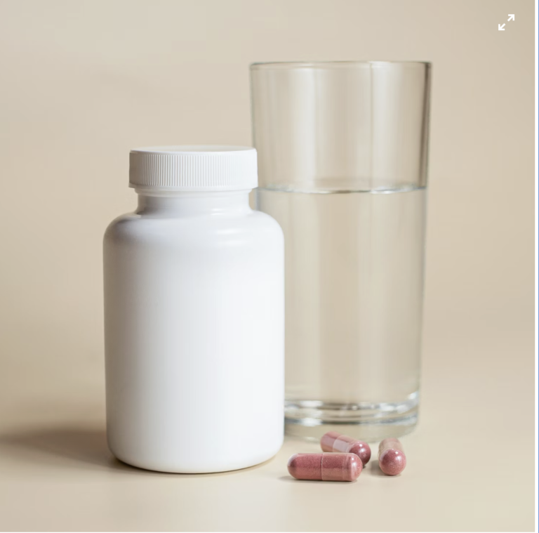 This photo shows prescription medicines beside a glass of water.