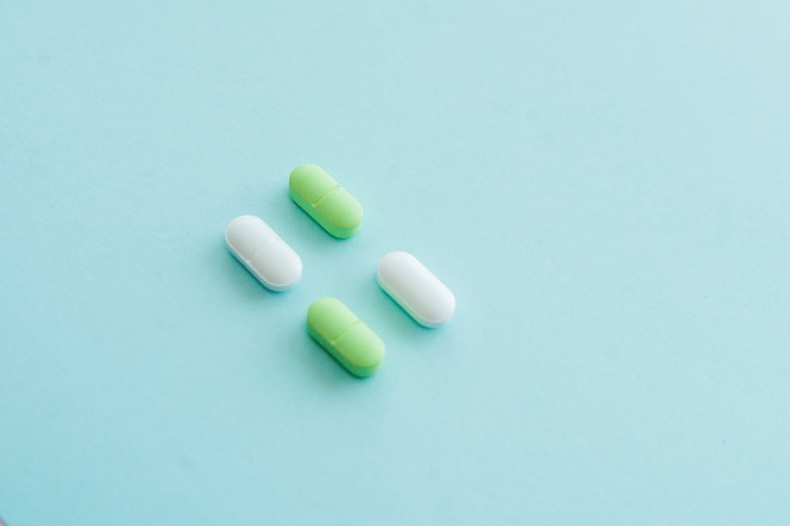 An image of green and white pills on a blue surface