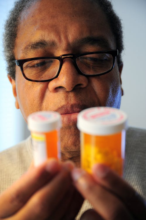 An image of a man looking closely at pill bottles in his hand