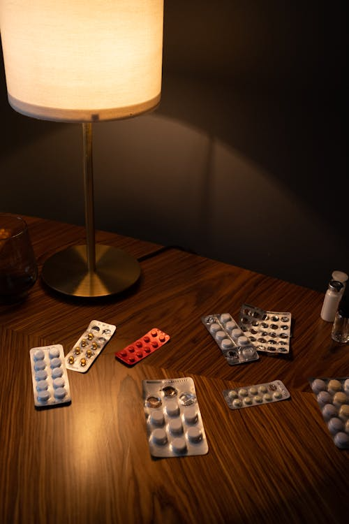 An image of pills and a lamp on a bedside table  