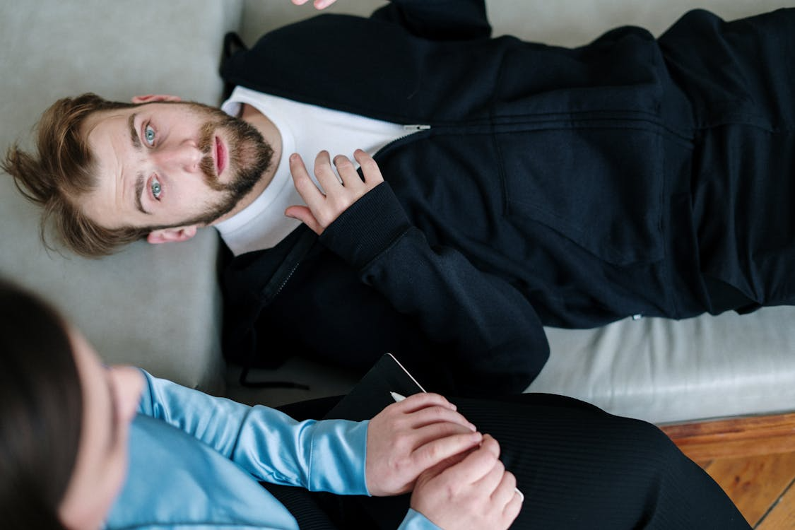 An image of a man lying down on a sofa while looking at the ceiling