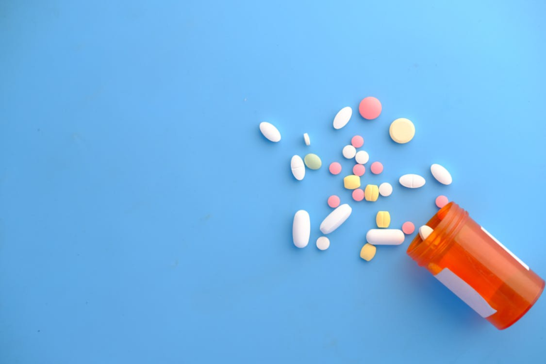 An image of an orange container and pills on a blue surface