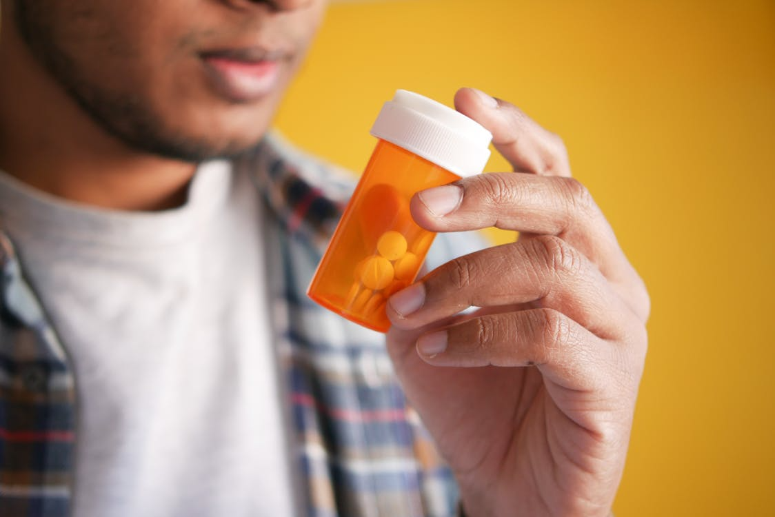 An image of a person holding an orange pill container   