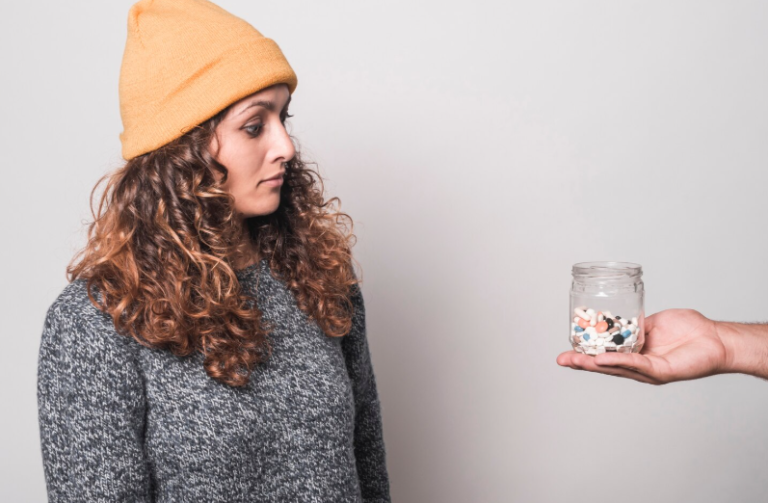 Woman appearing tired while observing pills in a man’s hand representing early addiction warning signs