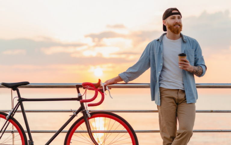 Man holding coffee during sunrise representing structured morning routine in recovery lifestyle