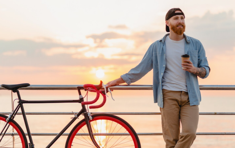 Man holding coffee during sunrise representing structured morning routine in recovery lifestyle