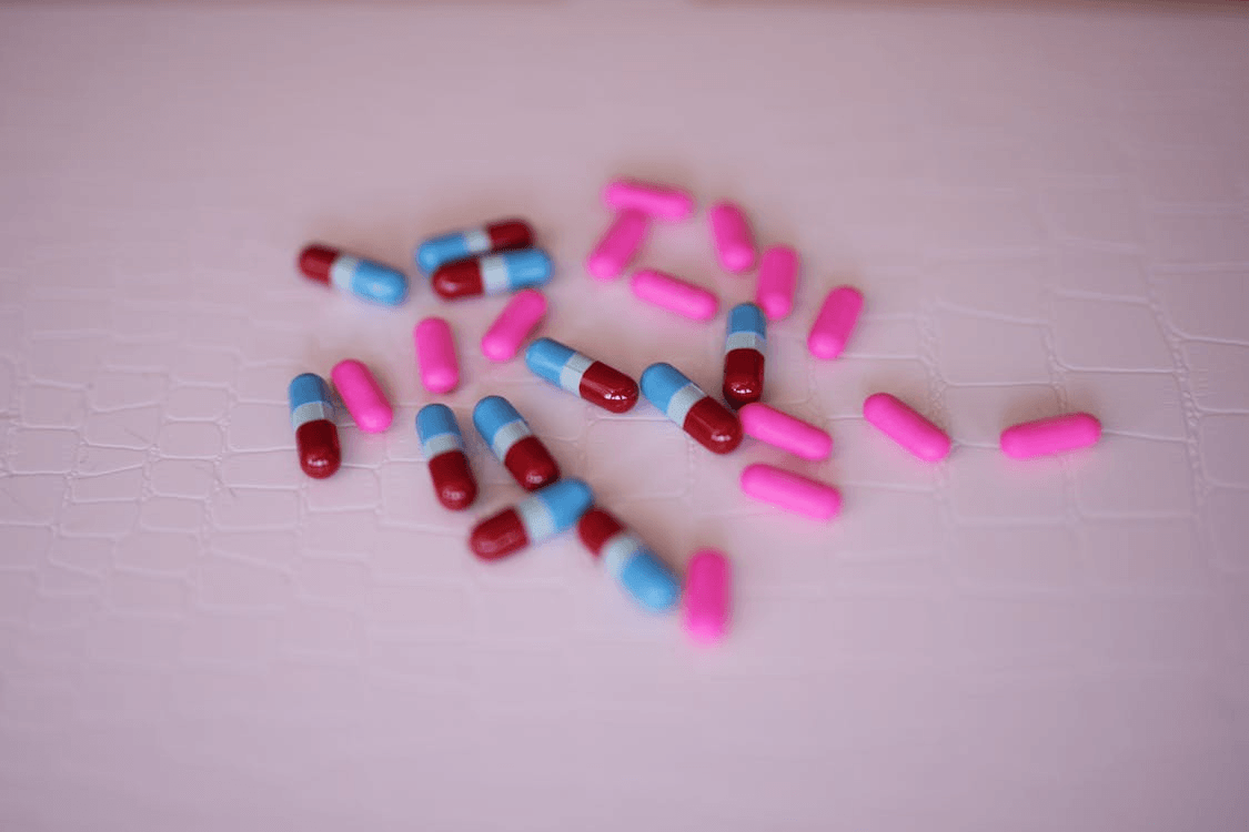 An image of pills on a pink surface