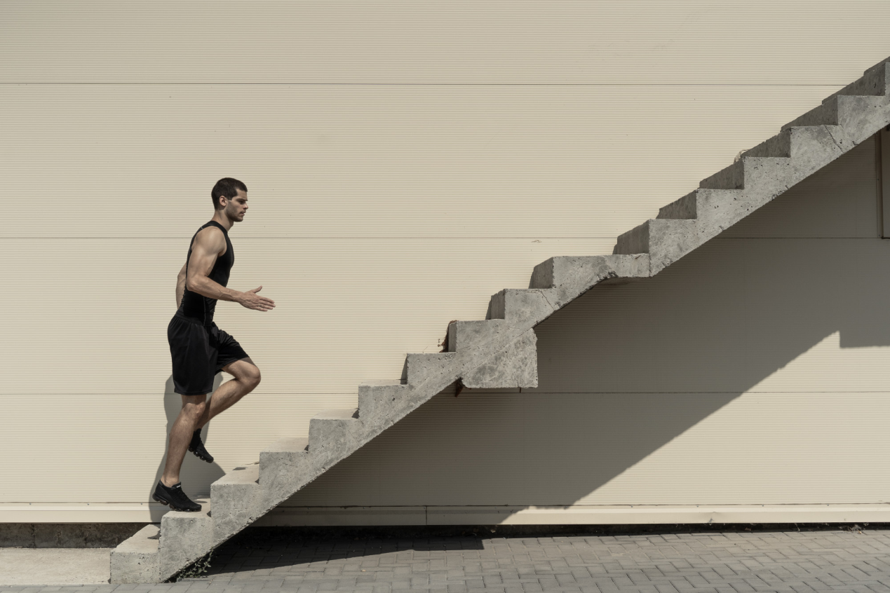 Man climbing stairs representing progress, goal achievement, and steady improvement in recovery