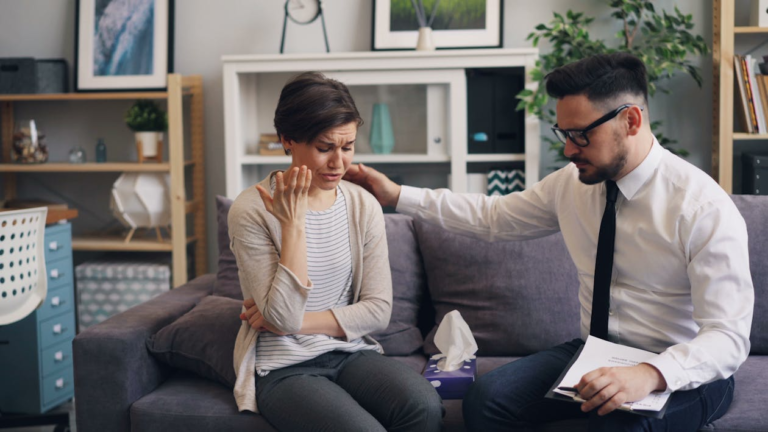 Addiction therapist consoling a woman during outpatient counseling session on a couch