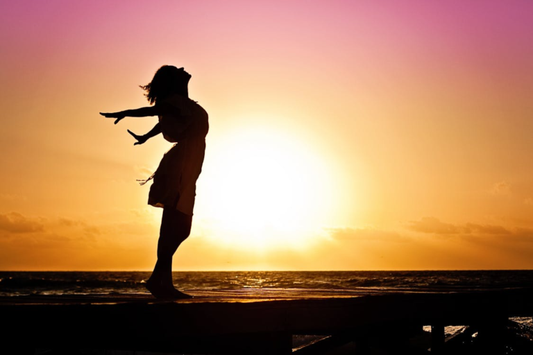 Silhouette of a woman during sunrise, feeling relaxed