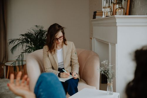 A therapist taking notes while listening during a private counseling session