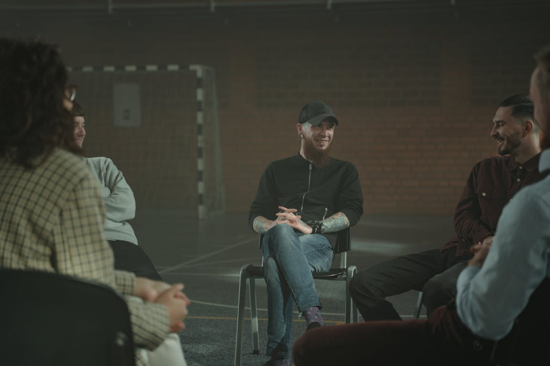 a smiling person talking to a group of peers during addiction recovery