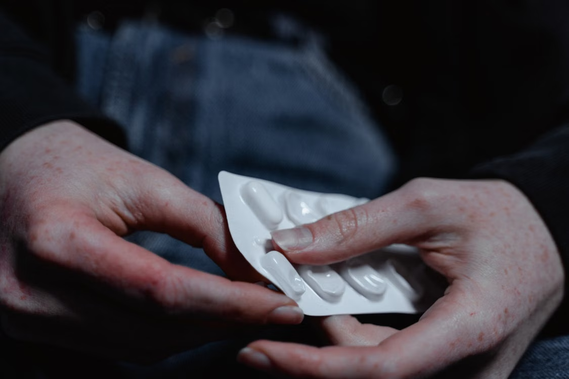 An image of a person taking out pills from a blister pack