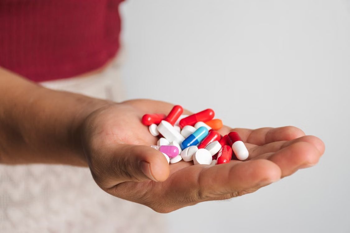 An image of a person holding pills in their hand  