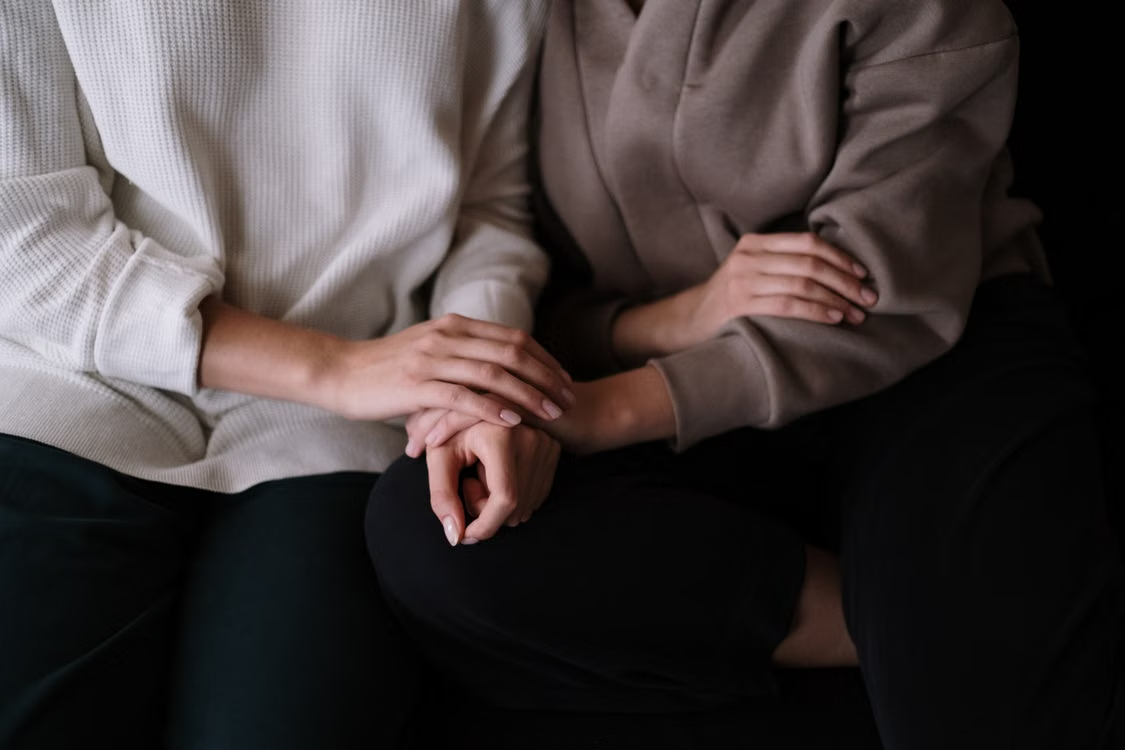two people holding each other's hands in support
