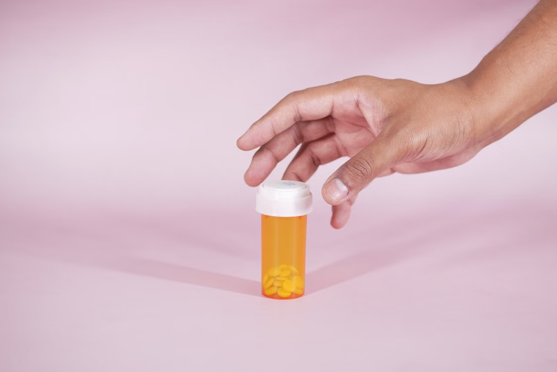 a person reaching for a bottle of medicine